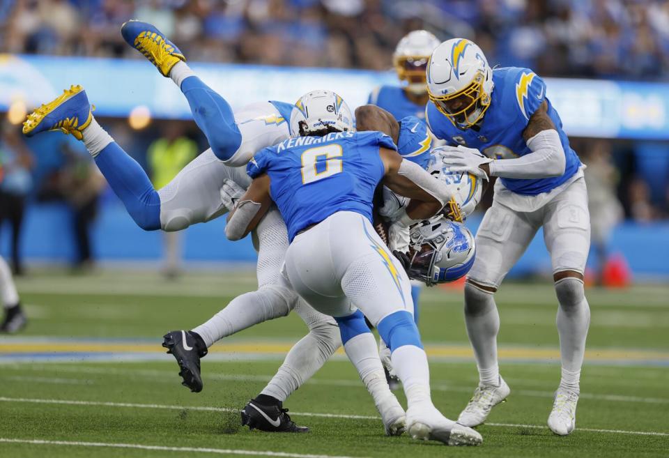 Lions running back Jahmyr Gibbs is tackled by Chargers linebackers Khalil Mack and Eric Kendricks and safety Derwin James Jr.
