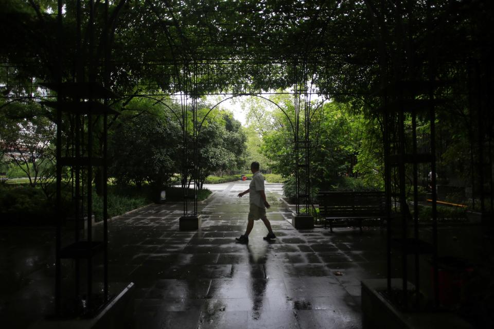 In this Sept. 4, 2012 photo, a man walks at Fuxing Park in Shanghai, China. Fuxing Park, southwest of People’s Square on the opposite side of the North-South Expressway, is a French-style park with fountains and gardens that once was part of the French Concession neighborhood during Shanghai’s colonial era. In the mornings, locals dance and practice tai-chi or martial arts here. (AP Photo/Eugene Hoshiko)