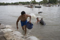 Central American migrants reach the shore on the Mexican side of the Suchiate River after wading across, on the the border between Guatemala and Mexico, in Ciudad Hidalgo, Mexico, Saturday, Oct. 20, 2018. After Mexican authorities slowed access through the border bridge to a crawl, hundreds of migrants are boarding the rafts or wading across the river and crossing into Mexico illegally. (AP Photo/Moises Castillo)