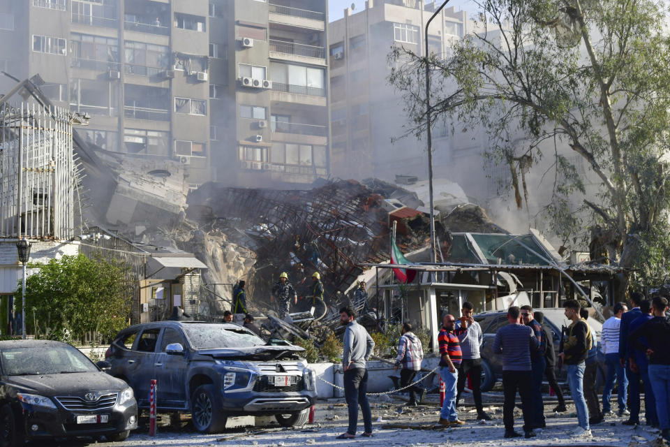 In this photo released by the official Syrian state news agency SANA, people gather near a destroyed building struck by Israeli jets in Damascus, Syria, Monday, April 1, 2024. An Israeli airstrike has destroyed the consular section of Iran's embassy in Syria, killing a senior Iranian military adviser and roughly a handful of other people, Syrian state media said Monday. (SANA via AP)