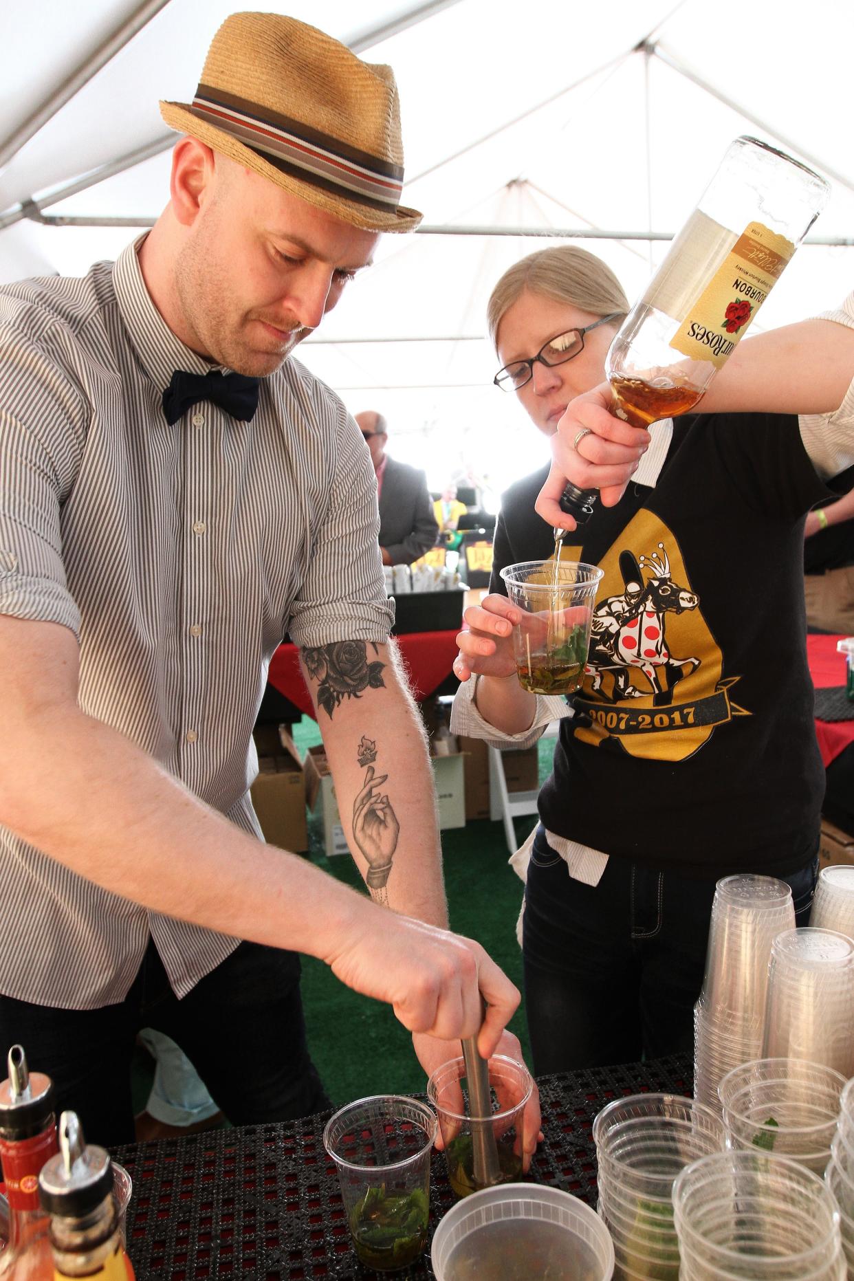 Alex Carroll and Kathryn Ramirez prepare mint julep drinks for waiting customers at Maxie's Derby Day party in 2017.