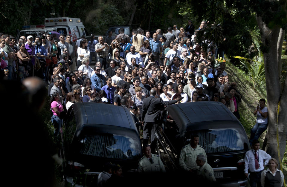 People attend the funeral of Monica Spear and her ex-husband Thomas Henry Berry at the East Cemetery in Caracas, Venezuela, Friday, Jan. 10, 2014. Robbers killed Spear, 29, a former Miss Venezuela, and her former husband Berry, 39, late Monday night on an isolated stretch of highway while the couple was returning to the capital by car with their 5-year-old daughter from a vacation. (AP Photo/Alejandro Cegarra)