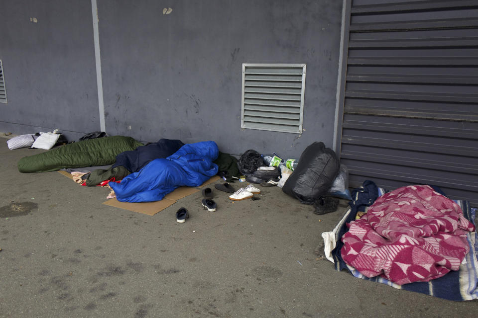 Migrants sleep on the pavement Thursday, Nov. 25, 2021 in Calais, northern France. Children and pregnant women were among at least 27 migrants who died when their small boat sank in an attempted crossing of the English Channel, a French government official said Thursday. French Interior Minister Gerald Darmanin also announced the arrest of a fifth suspected smuggler thought to have been involved in what was the deadliest migration tragedy to date on the dangerous sea lane.(AP Photo/Rafael Yaghobzadeh)