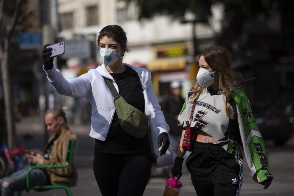 Two women take a selfie as they wear face masks in Tel Aviv, Israel, Sunday, March 15, 2020. ‏Israel has imposed a number of tough restrictions to slow the spread of the new coronavirus. Prime Minister Benjamin Netanyahu announced that schools, universities, restaurants and places of entertainment will be closed to stop the spread of the coronavirus. He also encouraged people not to go to their workplaces unless absolutely necessary. (AP Photo/Oded Balilty)