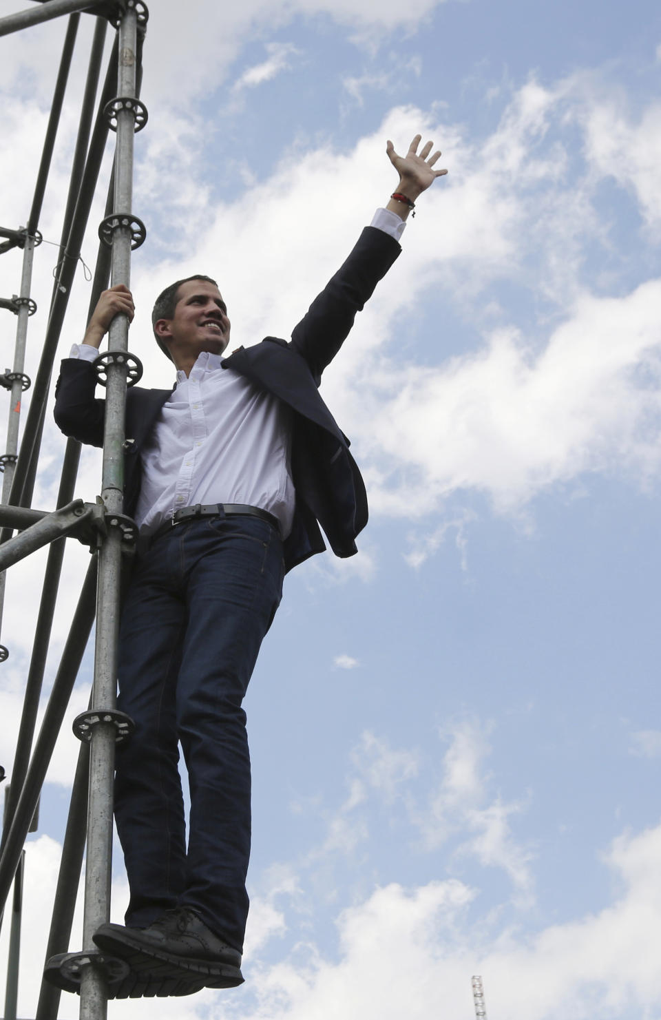 Venezuelan Congress President Juan Guaido, an opposition leader who declared himself interim president, waves to supporters from the stage's scaffolding after speaking to supporters during a rally demanding the resignation of Venezuelan President Nicolas Maduro in Caracas, Venezuela, Monday, March 4, 2019. The United States and about 50 other countries recognize Guaido as the rightful president of Venezuela, while Maduro says he is the target of a U.S.-backed coup plot. (AP Photo/Fernando Llano)