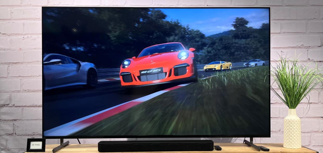  Sony XR-X90L TV on stand with red car on screen. 