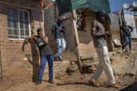 Residents of the Sjwetla informal settlement on the outskirt of the Alexandra township in Johannesburg stand outside their homes, Tuesday May 5, 2020. Up to 1600 South Africans living on the banks of the often flooding Jukskei river will be moved to less congested higher grounds in the coming months. South Africa begun a phased easing of its strict lockdown measures on May 1, and its confirmed cases of coronavirus continue to increase as more people are being tested. (AP Photo/Jerome Delay)