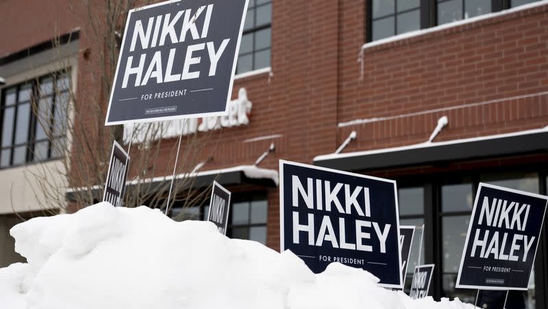Signs are visible on a large pile of snow before Republican presidential candidate Nikki Haley speaks at Toast in Ankeny, Iowa, on Thursday, Jan. 11, 2024.