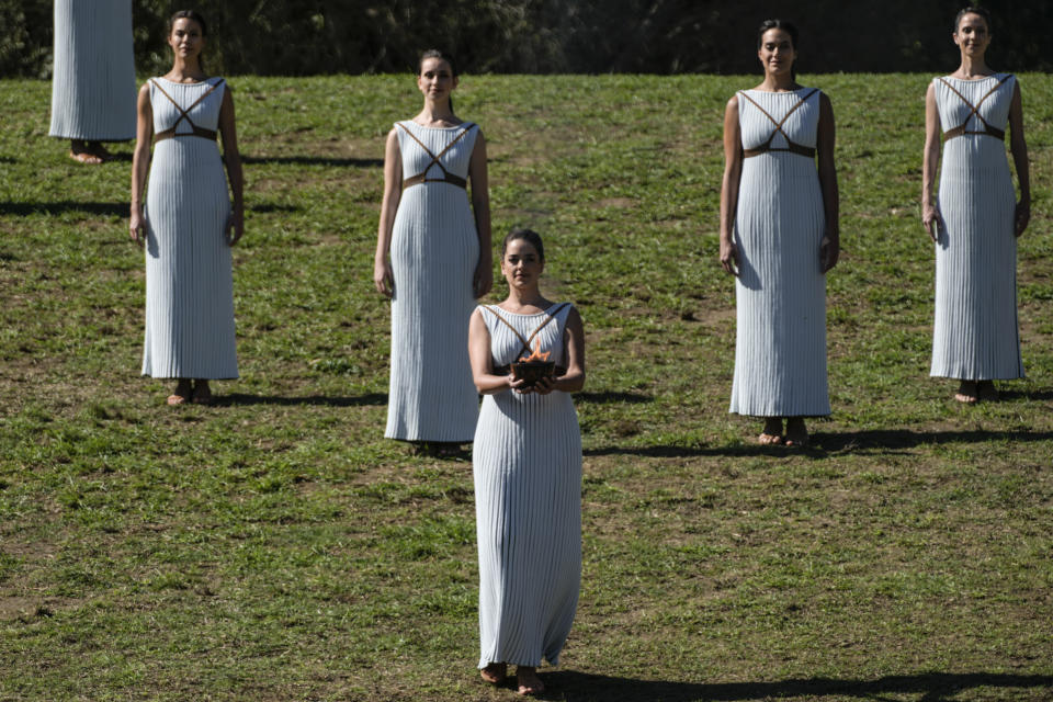 Greek actress Xanthi Georgiou, playing the role of the High Priestess, walks with the flame to first torchbearer, Greek alpine ski racer Ioannis Antoniou during the lighting of the Olympic flame at Ancient Olympia site, birthplace of the ancient Olympics in southwestern Greece, Monday, Oct. 18, 2021. The flame will be transported by torch relay to Beijing, China, which will host the Feb. 4-20, 2022 Winter Olympics. (AP Photo/Petros Giannakouris)