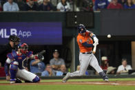 Houston Astros' Alex Bregman, right, hits a two-run triple as Texas Rangers catcher Jonah Heim reaches for the pitch during the first inning in Game 4 of the baseball American League Championship Series Thursday, Oct. 19, 2023, in Arlington, Texas. (AP Photo/Godofredo A. Våsquez)