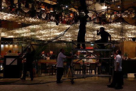 Workers raise a net to safeguard a glass window outside a hotel as Typhoon Haima approaches in Hong Kong, China, October 21, 2016. REUTERS/Bobby Yip