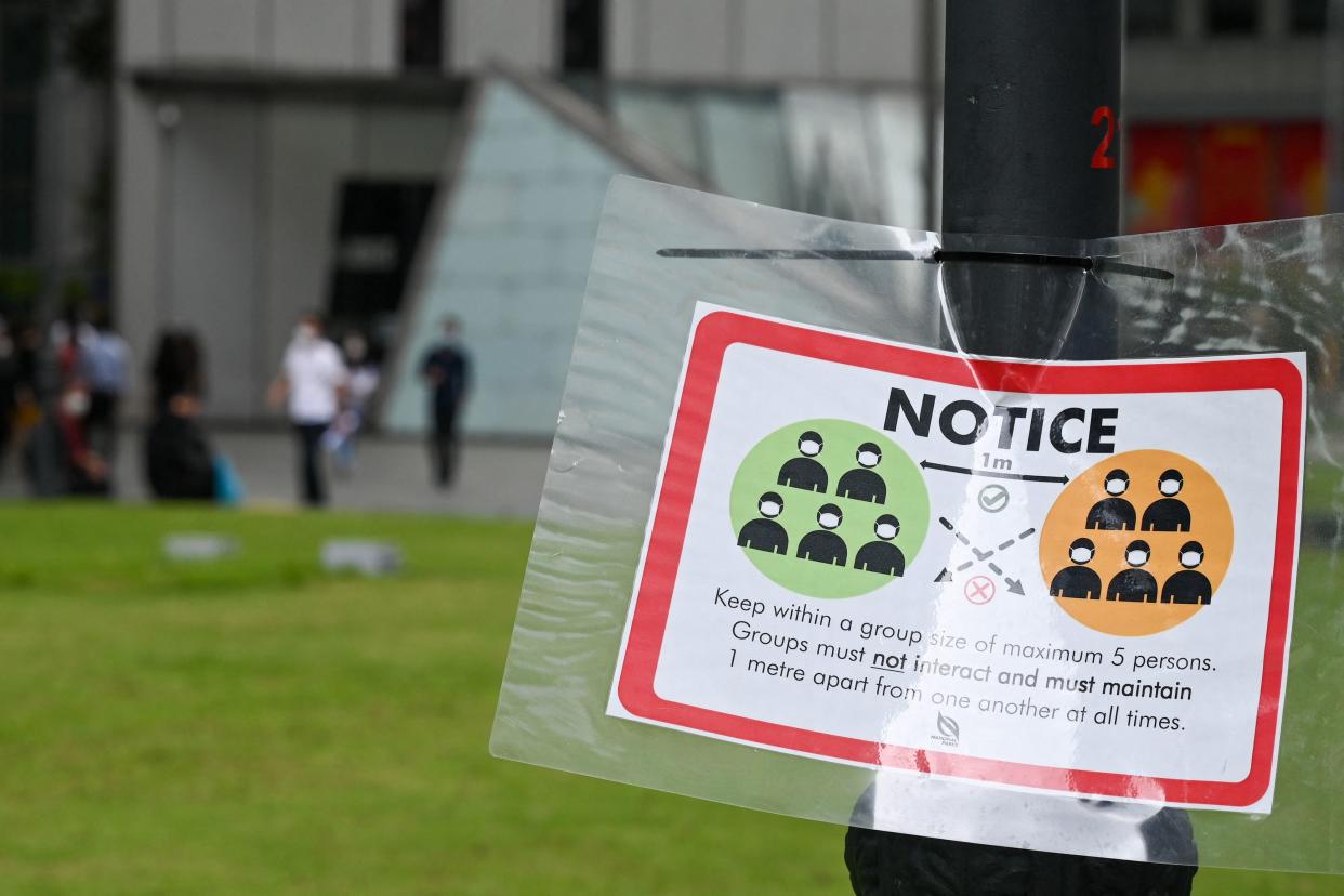 A notice warning people not to gather in groups larger than five persons as part of restrictions to hald the spread of the Covid-19 coronavirus is displayed at Raffles Place financial business district in Singapore on January 4, 2022. (Photo by Roslan RAHMAN / AFP) (Photo by ROSLAN RAHMAN/AFP via Getty Images)