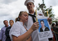U.S. Navy Petty Officer Second Class Keith Hoover, right, with his girlfriend Monica Matryba hold a photo of fellow sailor Jon Larimer at the Aurora Municipal Center, Sunday, July 22, 2012, in Aurora, Colo., during a prayer vigil for the victims of Friday's mass shooting at a movie theater. Twelve people were killed and dozens were injured in a shooting attack early Friday at the packed theater during a showing of the Batman movie, "The Dark Knight Rises." Police have identified the suspected shooter as James Holmes, 24. (AP Photo/Alex Brandon)