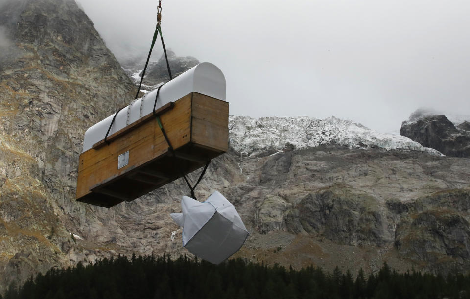 A box containing a radar is carried by a helicopter to the Planpincieux glacier located in the Alps on the Grande Jorasses peak of the Mont Blanc massif, above the Val Ferret, a popular hiking area on the south side of the Mont Blanc, near Courmayeur, northern Italy, Wednesday, Sept. 25, 2019. The radar will be used to monitor the glacier after Italian officials sounded an alarm Wednesday for threat that the fast-moving melting glacier is posing to the picturesque valley near the Alpine town of Courmayeur. The glacier, which spreads 1,327 square kilometers (512 square miles) across the mountain, has been moving up to 50 centimeters (nearly 20 inches) a day (AP Photo/Antonio Calanni)