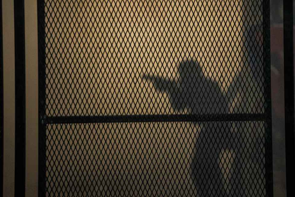 The outline of a federal officer behind a reinforced version of a fence (Nathan Howard / Getty Images file)