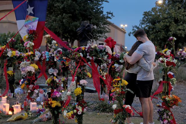 Joe Raedle/Getty People hug as they visit the memorial next to the Allen Premium Outlets