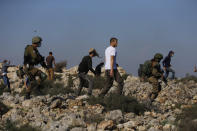 Israeli soldiers and settlers clash with Palestinians during a protest against the expansion of Jewish settlements near the West Bank town of Salfit, Monday, Nov. 30, 2020. In years to come, Israelis will be able to commute into Jerusalem and Tel Aviv from settlements deep inside the West Bank via highways, tunnels and overpasses that cut a wide berth around Palestinian towns. Rights groups say the new roads that are being built will set the stage for explosive settlement growth, even if President-elect Joe Biden's administration somehow convinces Israel to curb its housing construction. (AP Photo/Majdi Mohammed)