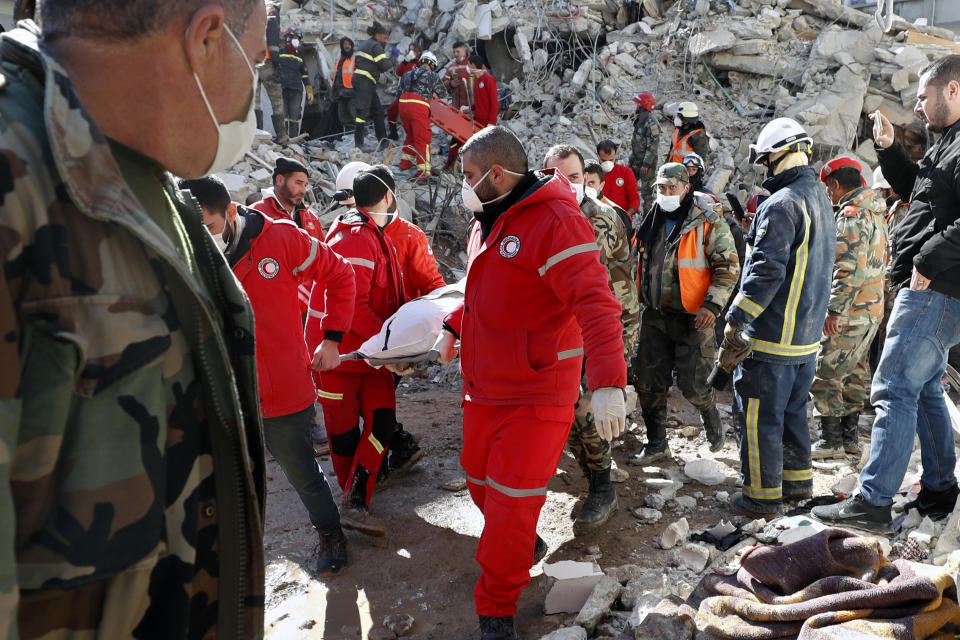 Rescue teams carry the body of a victim from a destroyed building after a devastating earthquake rocked Syria and Turkey, in the costal town of Jableh, Syria, Thursday, Feb. 9, 2023. The quake that razed thousands of buildings was one of the deadliest worldwide in more than a decade. (AP Photo/Omar Sanadiki)