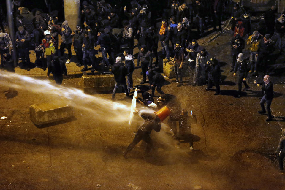 Riot police sprayed anti-government protesters with water cannons as they try to cross to the central government building during ongoing protests in Beirut, Lebanon, Saturday, Jan. 25, 2020. Hundreds of Lebanese gathered outside the central government building to reject the newly formed Cabinet, while some protesters breached tight security erected around it, removing a metal gate and barbed wire prompting a stream of water cannons from security forces. (AP Photo/Bilal Hussein)