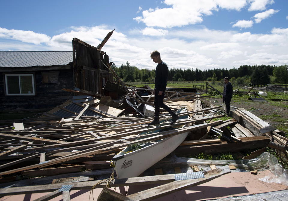 <p>Kyle Tully walks along beams from a barn that was destroyed by a tornado at his home on his cousin Christine Earle’s farm, as his boyfriend Colt Webber looks on, in Dunrobin, Ont., west of Ottawa, on Saturday, Sept. 22, 2018. The storm tore roofs off of homes, overturned cars and felled power lines in the Ottawa community of Dunrobin and in Gatineau, Que. (Photo from Justin Tang/The Canadian Press) </p>