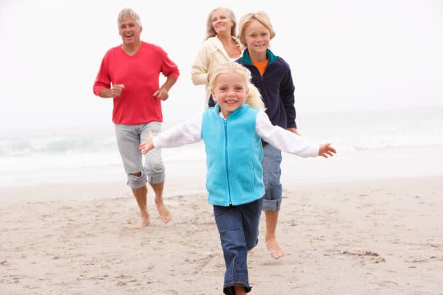 Grandparents And Grandchildren Running On Winter Beach Together
