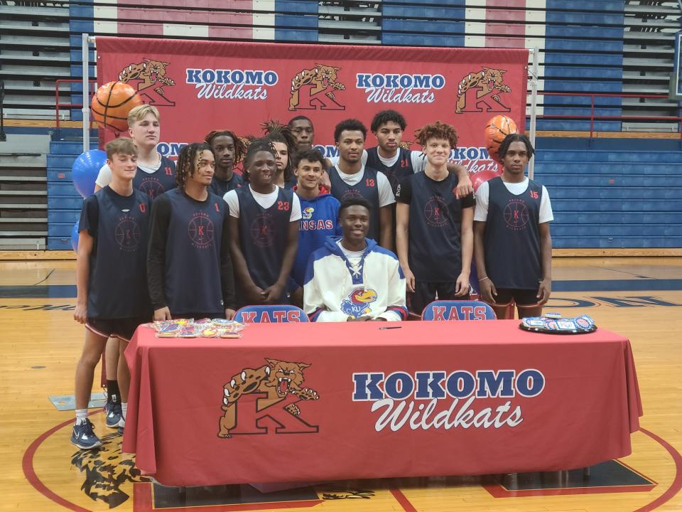 Kokomo big man Flory Bidunga (seated) is flanked by teammates after signing his letter of intent to attend Kansas.