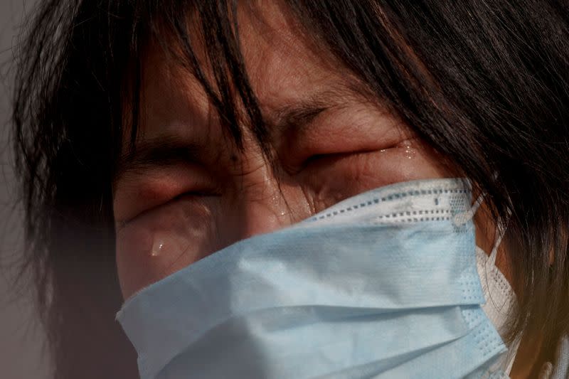 A mother reacts as she pleads with police to allow her daughter to pass a checkpoint for cancer treatment after she arrived from Hubei province at the Jiujiang Yangtze River Bridge in Jiujiang