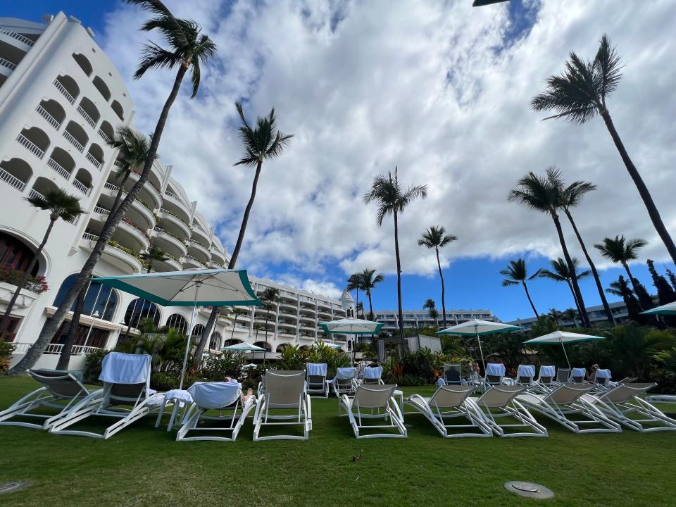 row of chairs, palm trees, and clouds in the sky