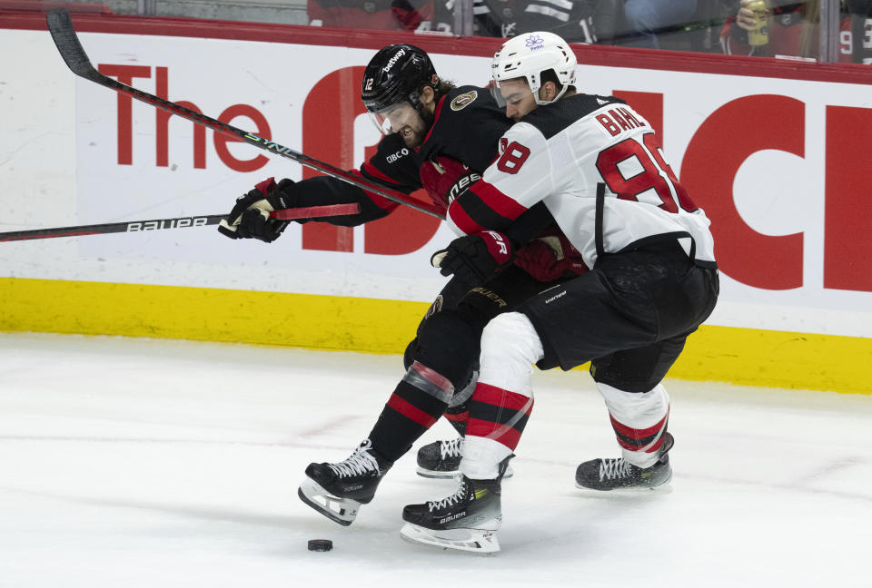 Ottawa Senators center Mark Kastelic, left, battles with New Jersey Devils defenseman Kevin Bahl , right, as he tries to control the puck during third-period NHL hockey game action in Ottawa, Ontario, Saturday, April 6, 2024. (Adrian Wyld/The Canadian Press via AP)