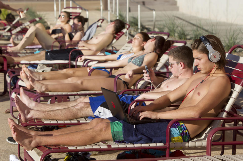 Arizona State students Joel Larson, 18, front, and Anthony Moffitt, 18, enjoy the Arizona sun by laying by the pool at Sun Devil Fitness Complex in Tempe. While most of the country is under a freeze, Phoenix is enjoying above average temperatures in the 80's. (AP Photo/The Arizona Republic, Cheryl Evans)