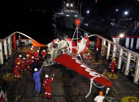 A section of the tail of AirAsia Flight QZ8501 passenger plane is seen on the deck of the rescue ship Crest Onyx, a day after it was lifted from the seabed, as crew try to lift it off the ship in Kumai Port, near Pangkalan Bun, Central Kalimantan January 11, 2015. REUTERS/Darren Whiteside