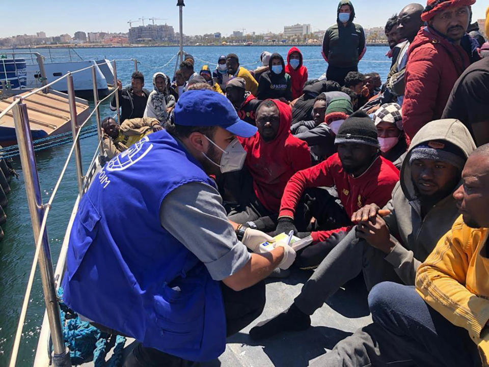 Aid workers for the International Organization for Migration provide assistance to migrants who were intercepted off the Libyan coast, at the Abu Sitta disembarkation point in Tripoli, Sunday, May 9, 2021. The organization said that more than 700 migrants were intercepted Sunday by the Libyan coast guard off the coast of the North African country, and at least 5 people had drowned when a boat carrying at least 45 migrants capsized. (International Organization for Migration via AP)