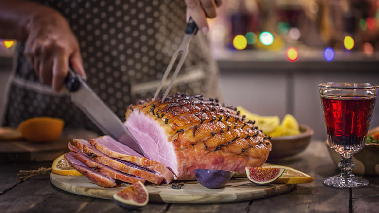 cutting glazed ham on board