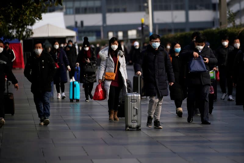 Passengers wearing masks walk at the Shanghai railway station