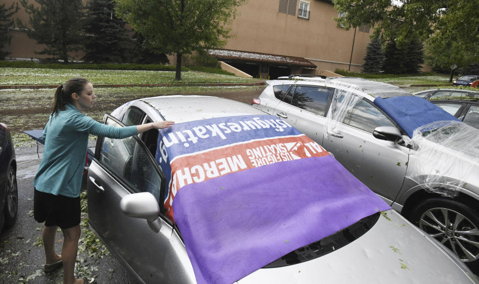 Some staffers at the World Figure Skating Museum and Hall of Fame had their windows shattered during a hail storm Monday, Aug. 6, 2018, in Colorado Springs, Colo. Ingrid Benson goes back to get her belongings from her car after the storm. (Jerilee Bennett/The Gazette via AP)