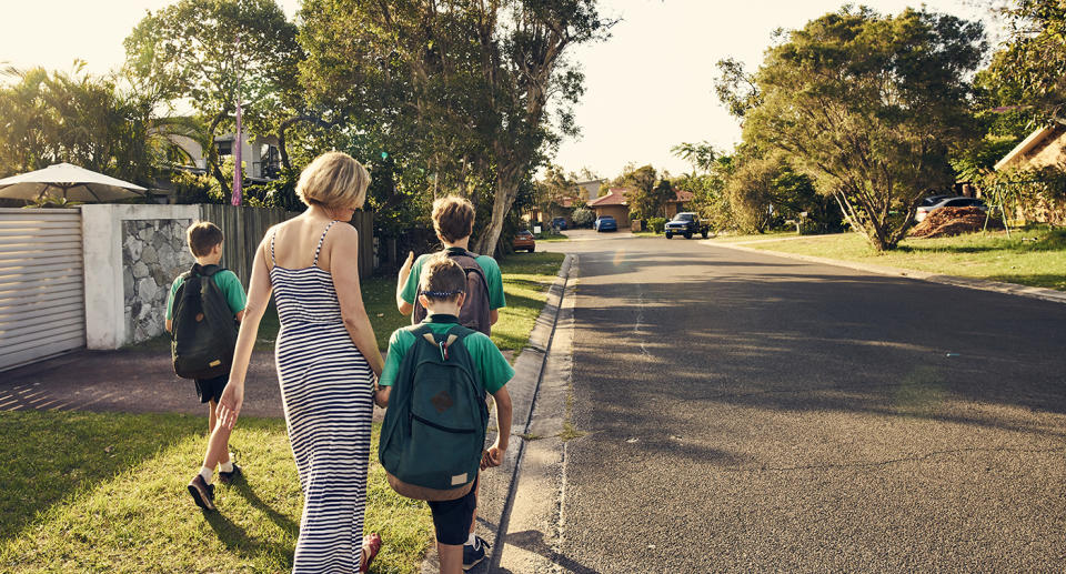 A group of children and a woman walk along a suburban road. Source: Getty Images