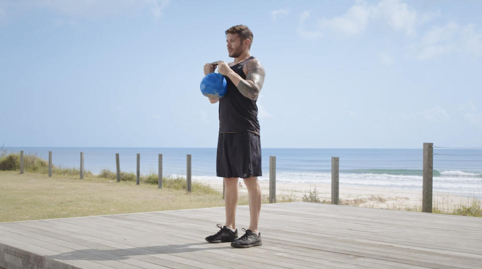 Luke Zocchi performs a goblet squat with a kettlebell