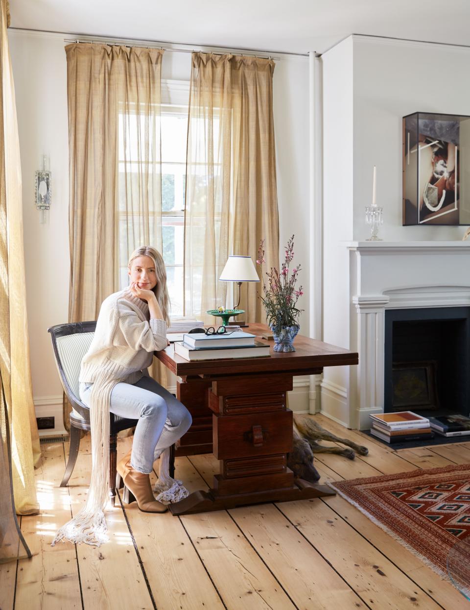 Designer Michelle R. Smith with her dog, Ingy, at home in Bellport, New York; the leaves of her antique Charles Dudouyt table open to create a double desk whenever her team comes to visit.