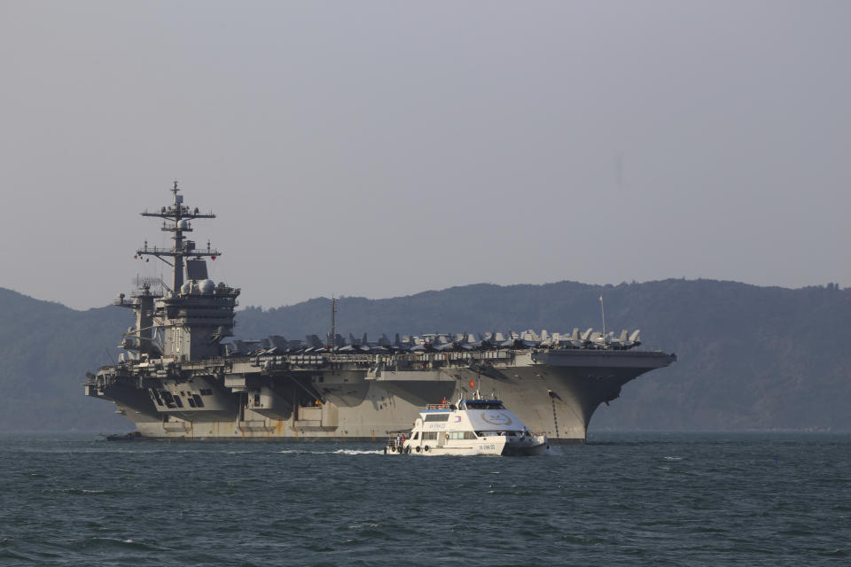 FILE - In this Monday, March 5, 2018, file photo, a Vietnamese passenger boat sails past U.S aircraft carrier USS Carl Vinson as it docks in Danang Bay, Vietnam. Over this last week, China demanded the United States stop sending ships and military aircraft close to its South China Sea island claims during talks to prepare for a meeting between President Donald Trump and President Xi Jinping later this month. (AP Photo/ Hau Dinh, File)