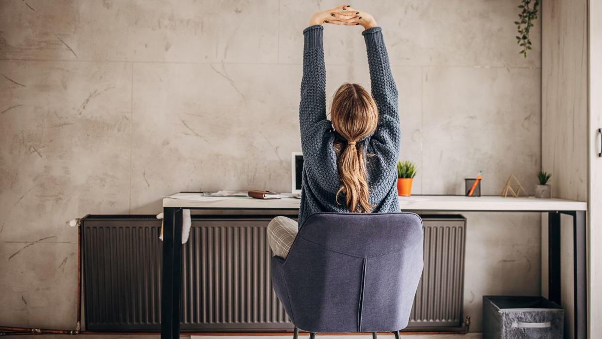  Woman stretches at desk. 