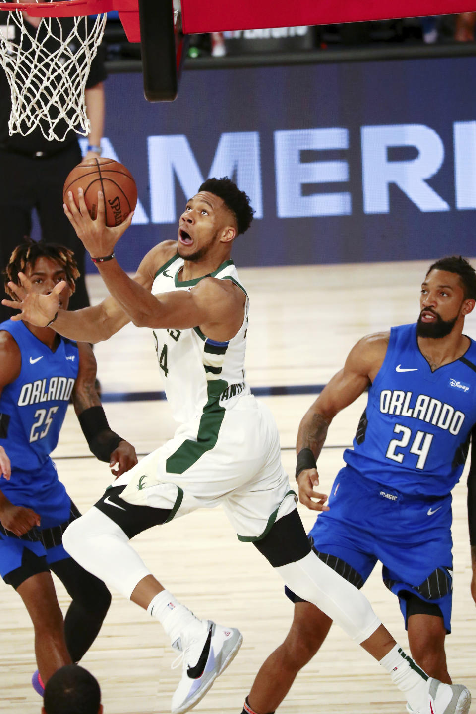 Milwaukee Bucks forward Giannis Antetokounmpo (34) shoots between Orlando Magic forward Wes Iwundu (25) and forward Khem Birch (24) during the first half of Game 1 of an NBA basketball first-round playoff series, Tuesday, Aug. 18, 2020, in Lake Buena Vista, Fla. (Kim Klement/Pool Photo via AP)