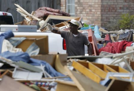 Billy Bethley throws flood damaged floor board on to a pile of debris in Prairieville, Louisiana, U.S., August 22, 2016. REUTERS/Jonathan Bachman