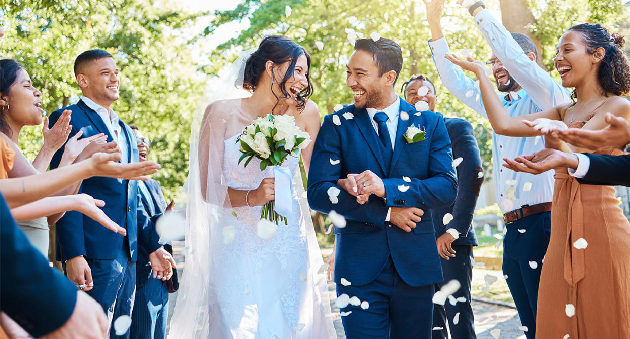 Couple getting married in wedding, surrounded by guets. (Getty Images)