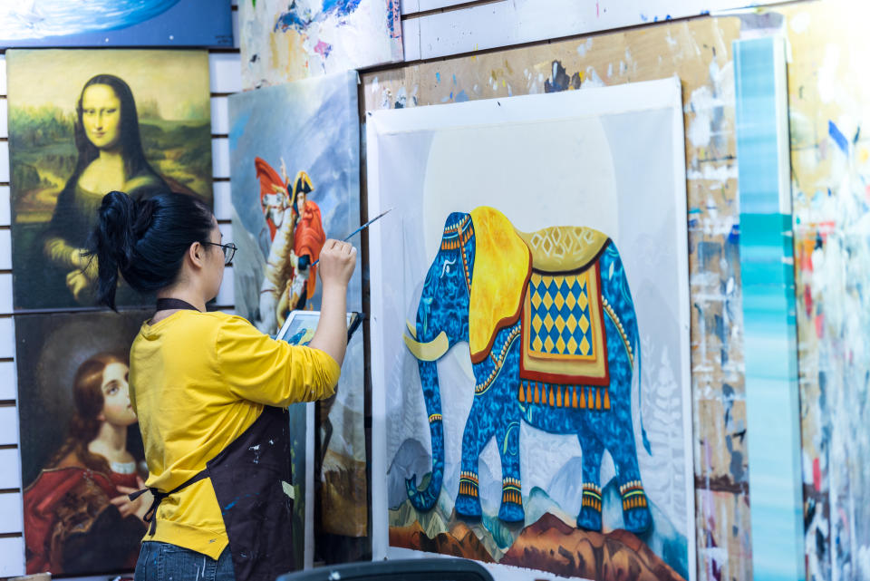A female oil painting artist painting on a canvas in the Dafen Oil Painting Village, Shenzhen, Guangdong Province, China. (Photo: Gettyimages)