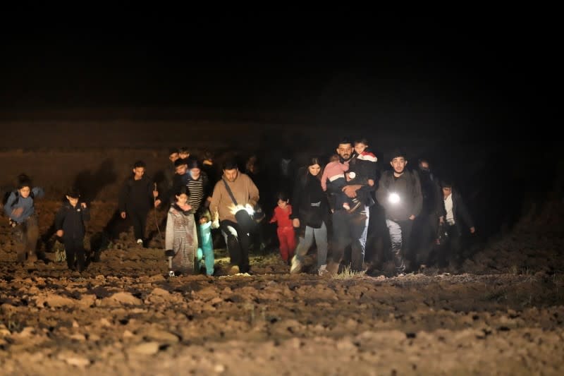 Migrants cross a field next to the Belarus-Latvia border near Vorzova