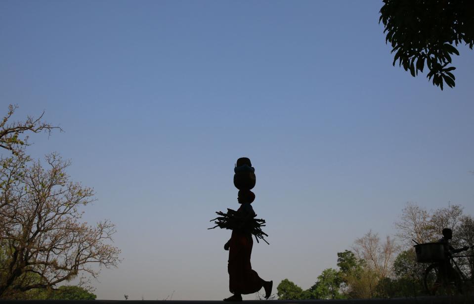 In this April 15, 2014 photo, a woman, who lives near an open pit coal mine, walks to her home after collecting wood and fruit from nearby forests at Gare village near the industrial city of Raigarh, Chhattisgarh state, India. While India’s rapid economic growth over the past decade has boosted the incomes and living standards of millions - mostly city-dwellers - the environmental impact has often been ignored and the rural poor have been left behind. (AP Photo/Rafiq Maqbool)