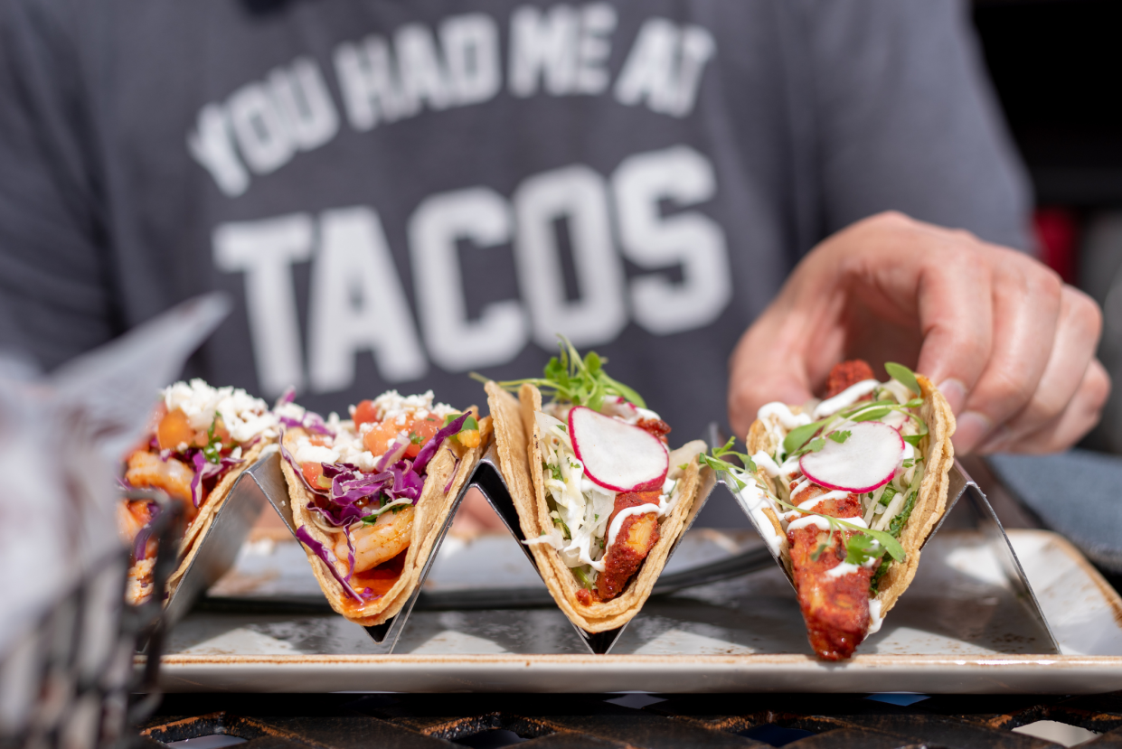 Man Picking up a Taco to Eat, Out of Four, Selective Focus