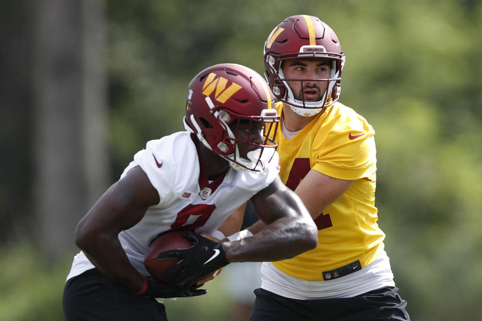 Washington Commanders quarterback Sam Howell, right, hands the ball off to running back Brian Robinson (8) during an NFL football practice at Inova Sports Performance Center in Ashburn, Va., Monday, Aug. 22, 2022. (AP Photo/Luis M. Alvarez)