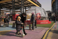 Residents bring their children visit to a mall next to a venue which host the men's and women's ice hockey games at the 2022 Winter Olympics in Beijing, Thursday, Feb. 10, 2022. The possibility of a large outbreak in the bubble, potentially sidelining athletes from competitions, has been a greater fear than any leakage into the rest of China. (AP Photo/Andy Wong)