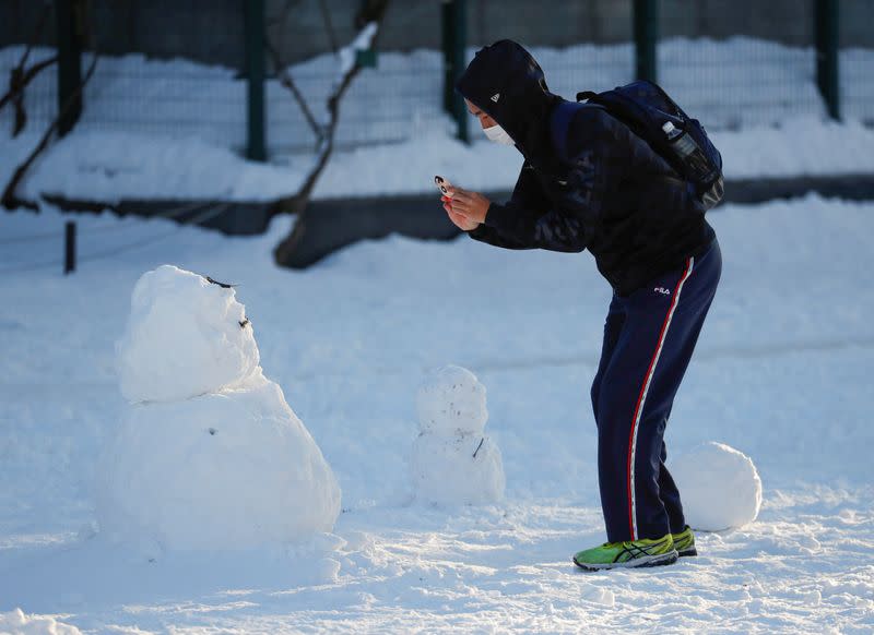 A man wearing protective mask takes photo of a snowman at Sapporo Odori Park in Sapporo, Hokkaido